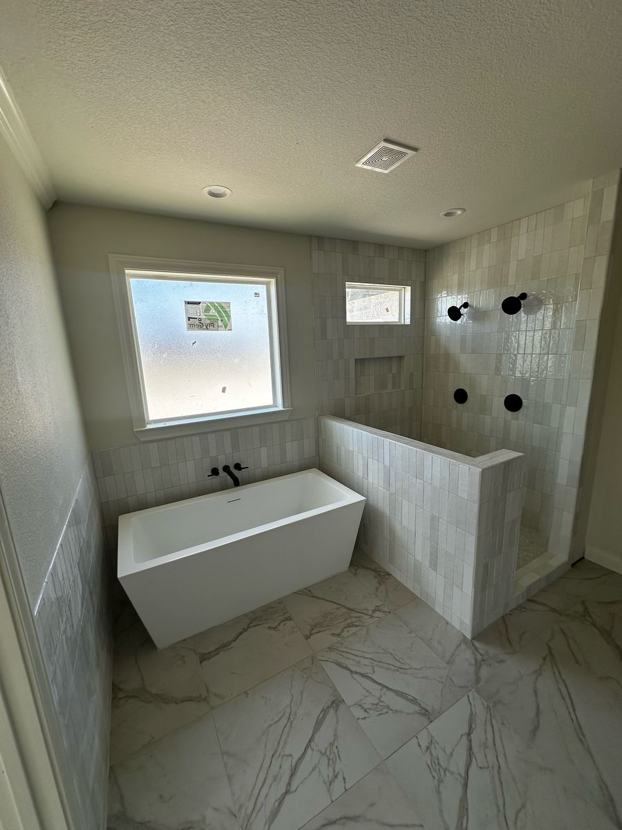 Project Pilot project: Bathroom with a white freestanding tub next to an open walk-in shower with a tiled half wall and matte black fixtures