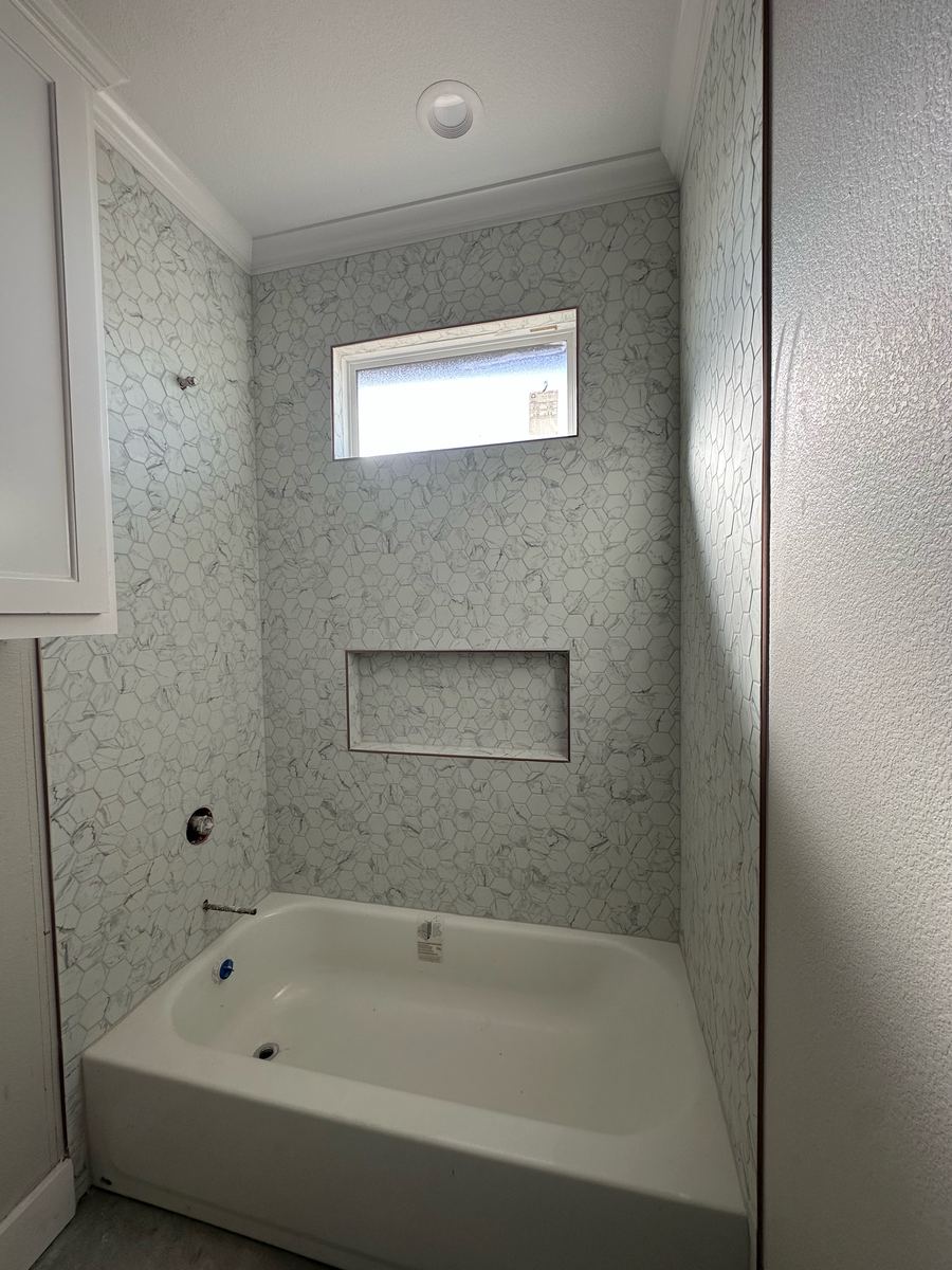 Project Pilot project: Tub and shower combination with white marble-look hexagon wall tile, a recessed niche, and a window above