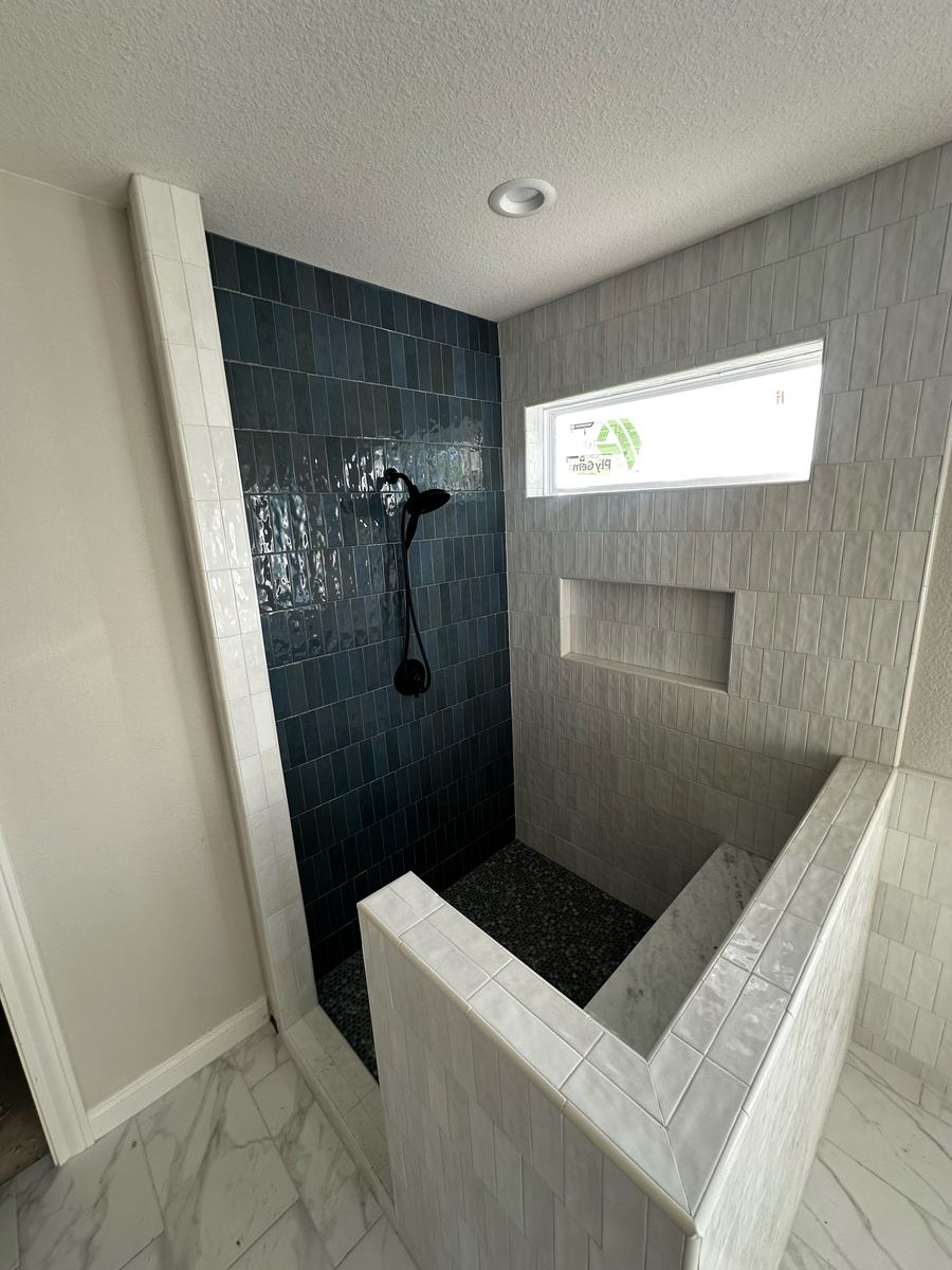 Project Pilot project: Walk-in shower with a navy blue tile accent wall, matte black handheld shower, recessed niche, and tiled bench